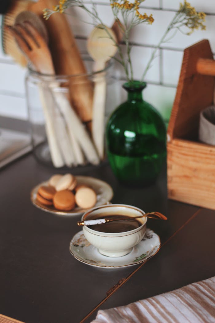 Charming kitchen counter setup with a teacup, macaroons, and rustic kitchenware for a cozy feel.