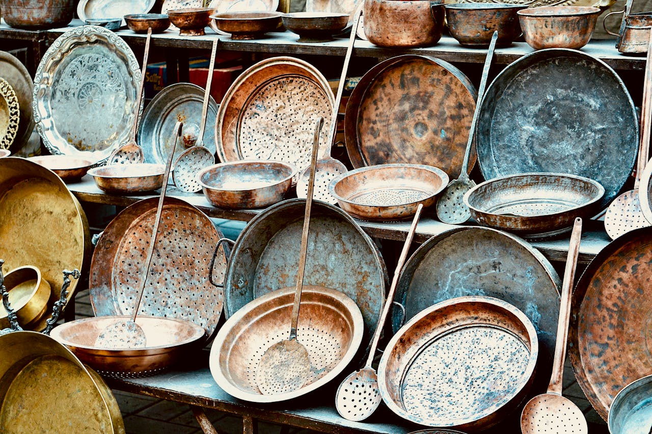 An assortment of vintage copper kitchenware displayed outdoors, showcasing rustic charm.